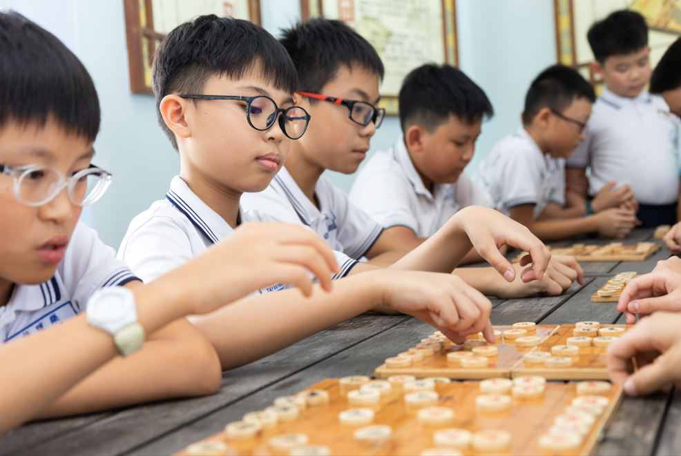 Two young students in white uniforms playing chess.